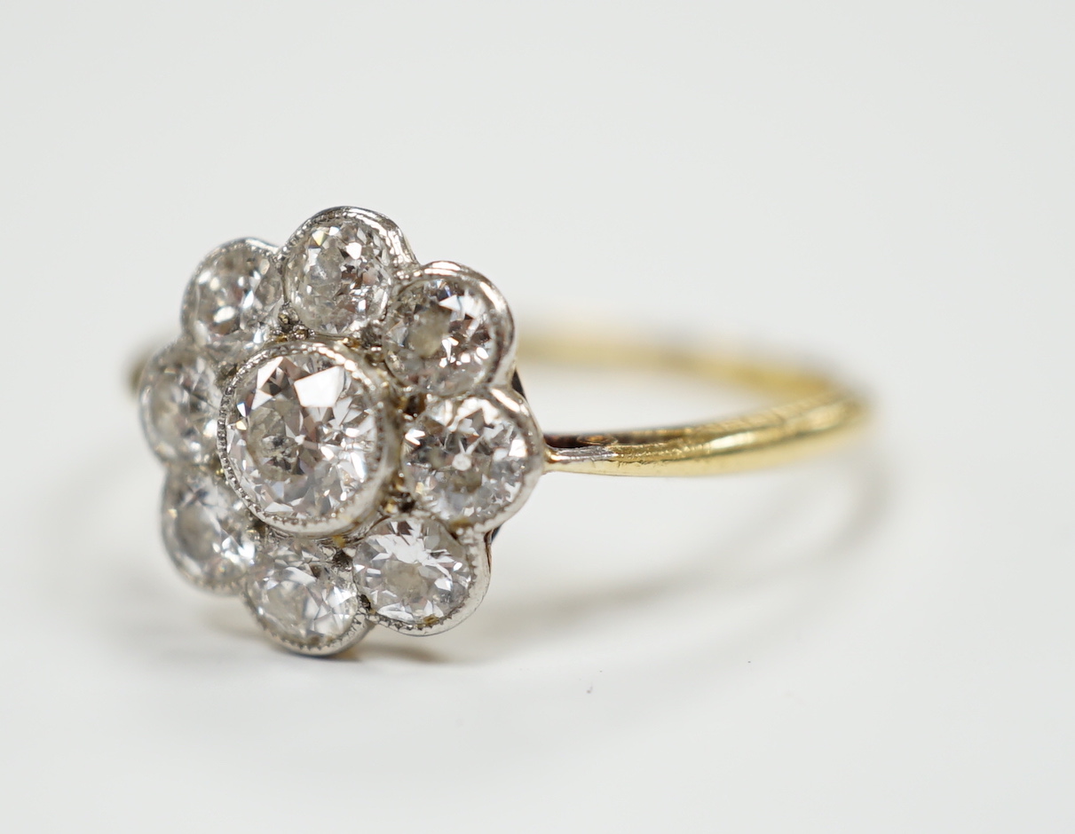 A 1930's/1940's 18ct and nine stone millegrain set diamond set flower head cluster ring, size P, gross weight 2.4 grams.